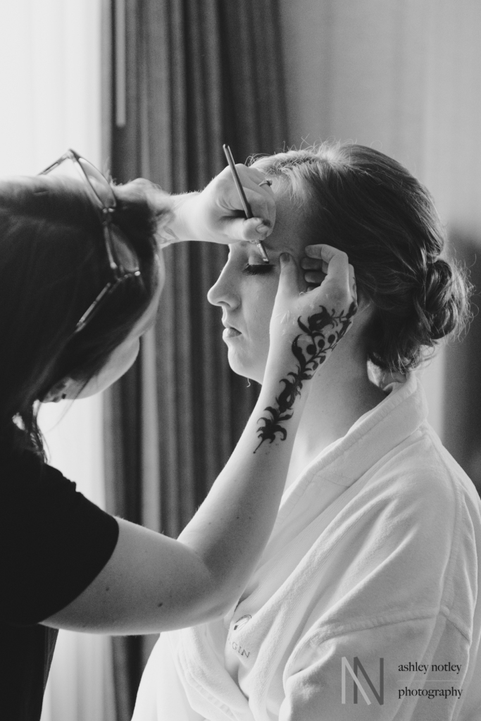 Bride getting her makeup done with tattoo on her hand