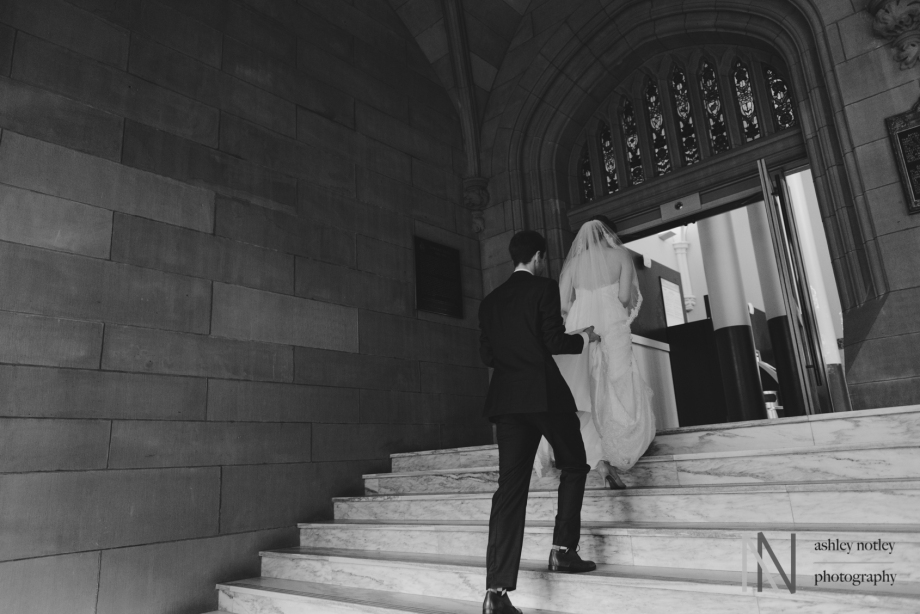 Groom carrying Bride's train up the stairs at the Canadian Museum of Nature