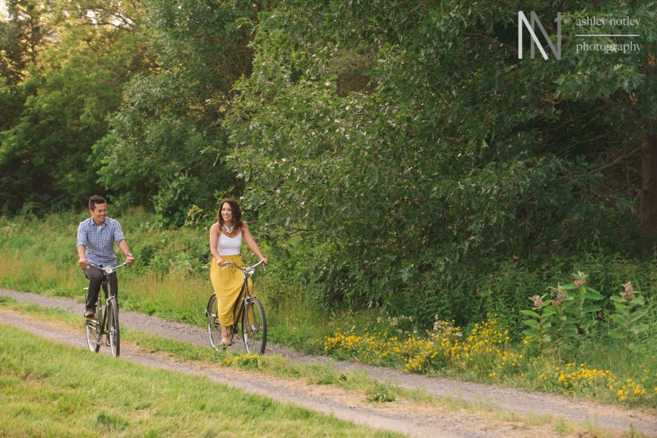 Couple biking during their engagement photo session at the experimental farm