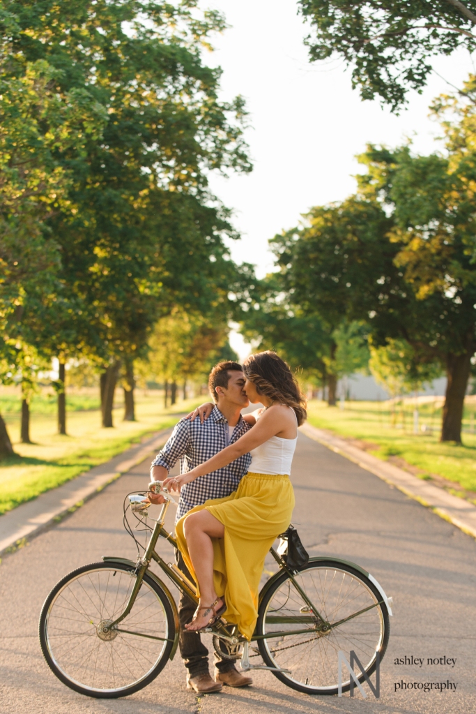 Couple sitting on a vintage Raleigh bike on a street lined with trees at the Experimental Farm