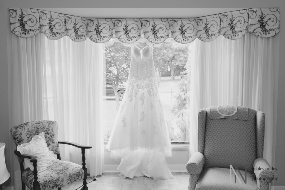 Bride's dress hanging in window in black and white