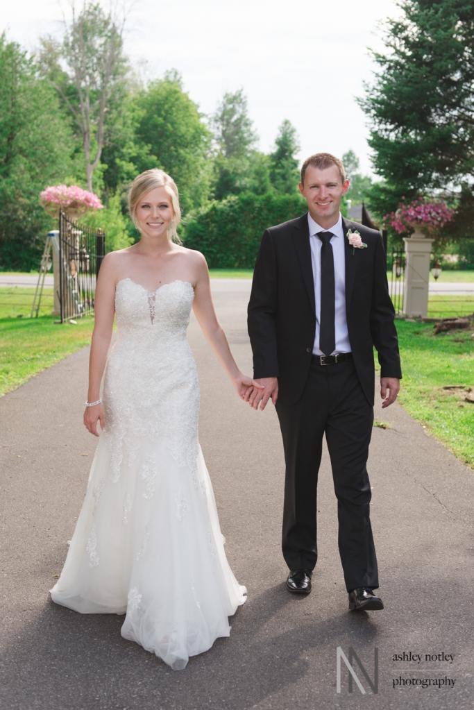 Bride and groom walking hand in hand down Emerald Links driveway