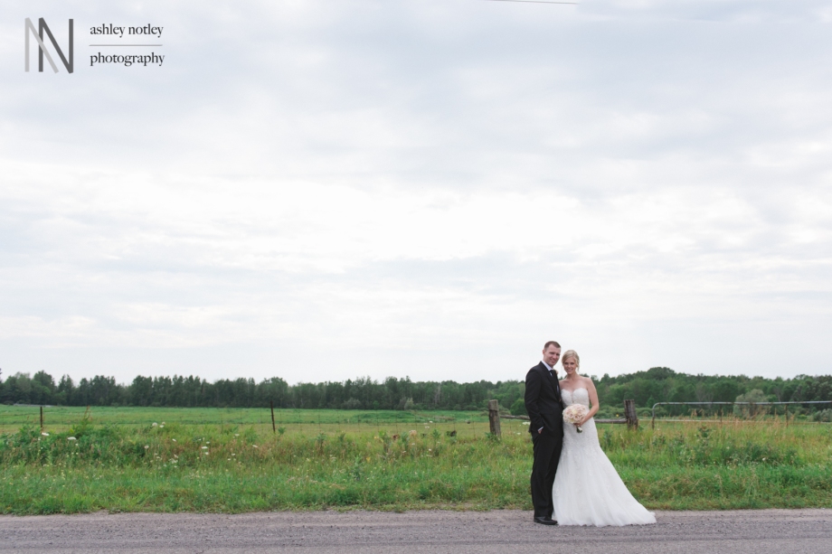 Bride and groom in field with moody sky