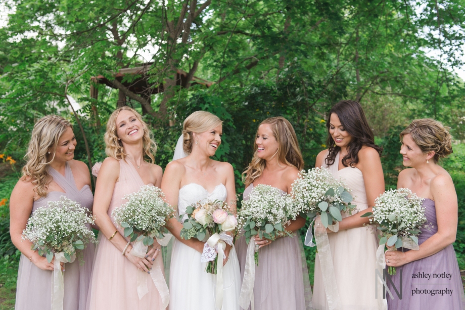 Bride and bridesmaids in pastels laughing among the trees