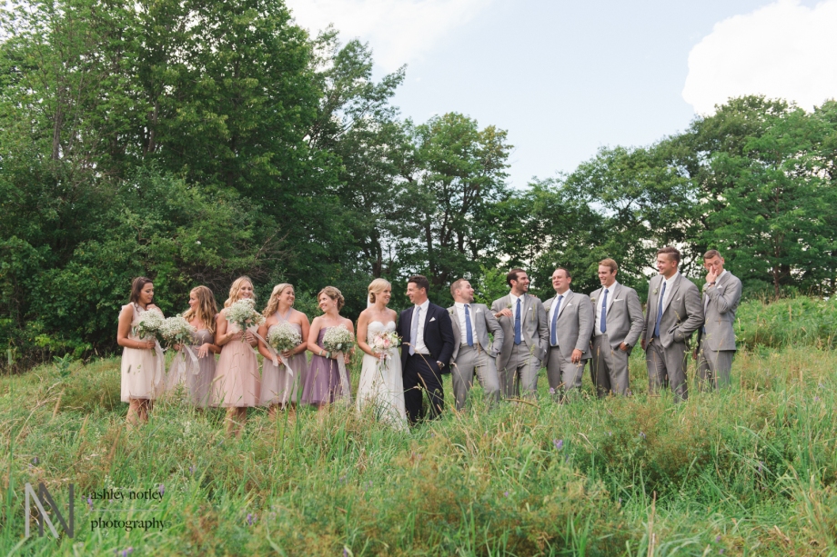 Wedding party in tall grass laughing together