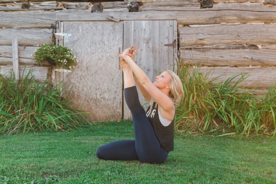 seated hamstring stretch in front of an old barn